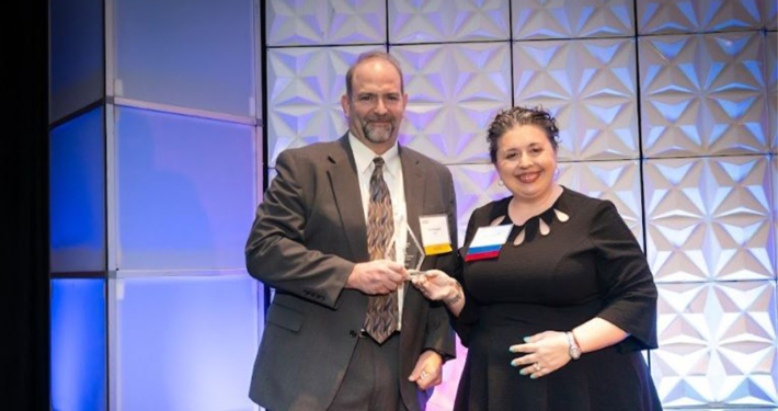 ATCS' Eric Mongelli accepting coprorate award on stage at an awards gala