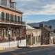 A street scene featuring a building on the left and a mountain rising in the background.