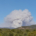 A thick plume of smoke from a fire is visible far away on the horizon.