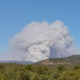 A thick plume of smoke from a fire is visible far away on the horizon.