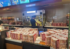 lots of empty popcorn bags on the concessions counter at movie theater. Concessions attendant making more.