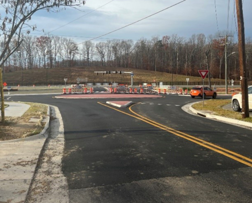 A road with a construction site and several cars parked on side of street