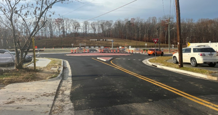 A road with a construction site and several cars parked on side of street