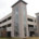 Large multi-story parking garage with tall glass-panel stair towers and open parking levels. Modern, urban design with a neutral tone under a cloudy sky.