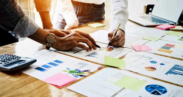 businessmen holding a pen pointing to paper graph on desk