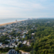 Aerial view of a beach town featuring houses, trees, and sandy shores under a clear blue sky